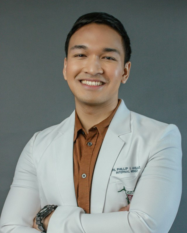 Karl Phillip L. Avillo, MD, in a white coat embroidered with his name and Internal Medicine.
